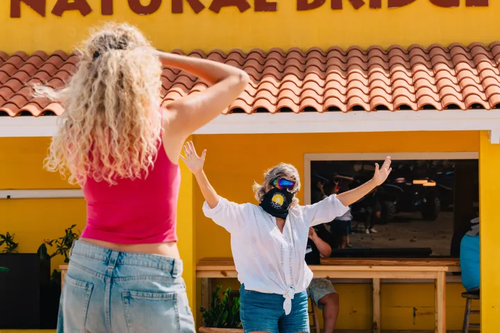 Two people posing in front of yellow building with 'Natural Bridge' sign.