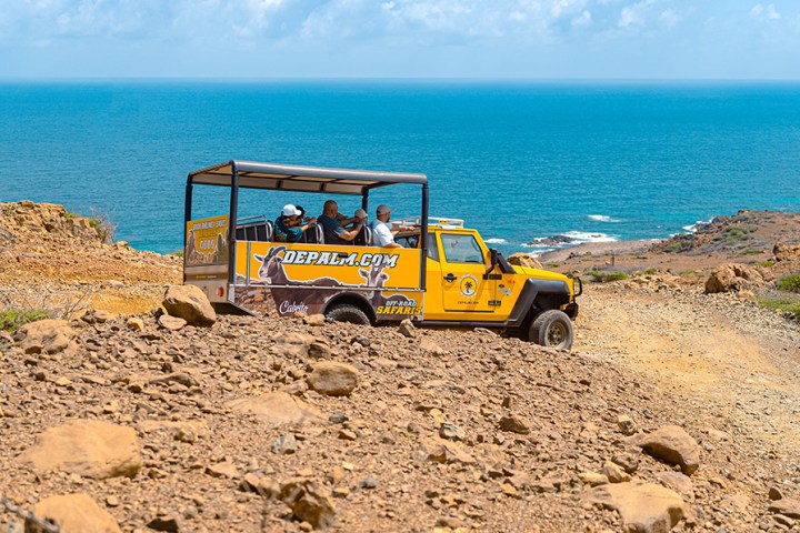 a tractor on a rocky beach next to the ocean