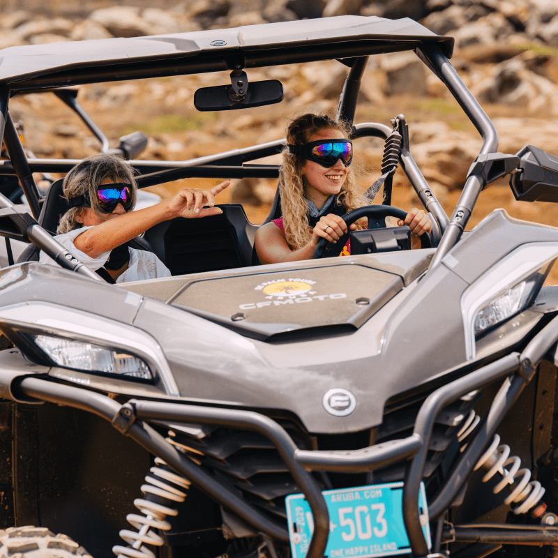 Two people driving a rugged off-road vehicle on a rocky terrain.