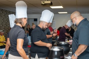 a group of people standing in a kitchen preparing food