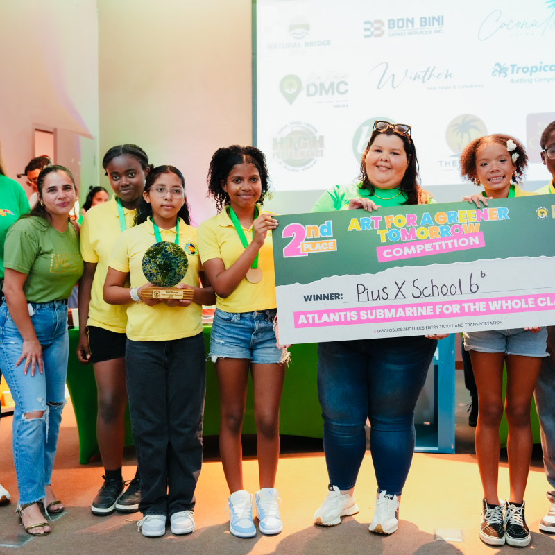 Group holding a large check reading '2nd Place Art for a Greener Tomorrow Competition' in a brightly lit room.