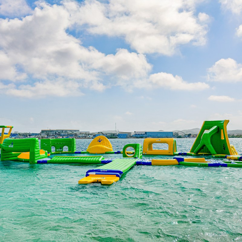 Colorful inflatable water park on a calm sea with a bright, partly cloudy sky.