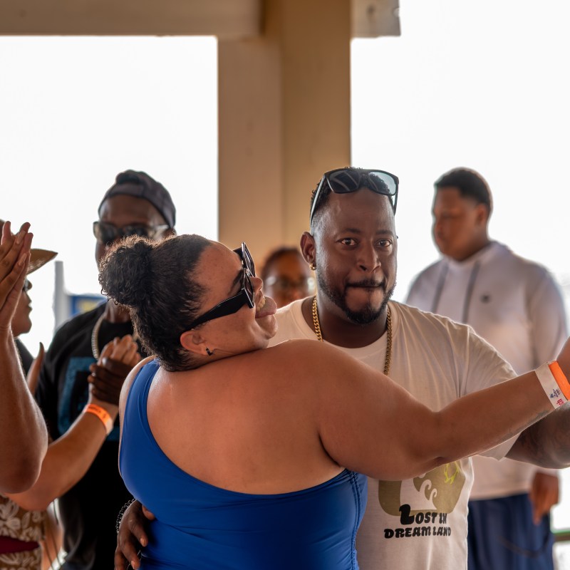 A couple dances enthusiastically at a social event while others watch and clap.