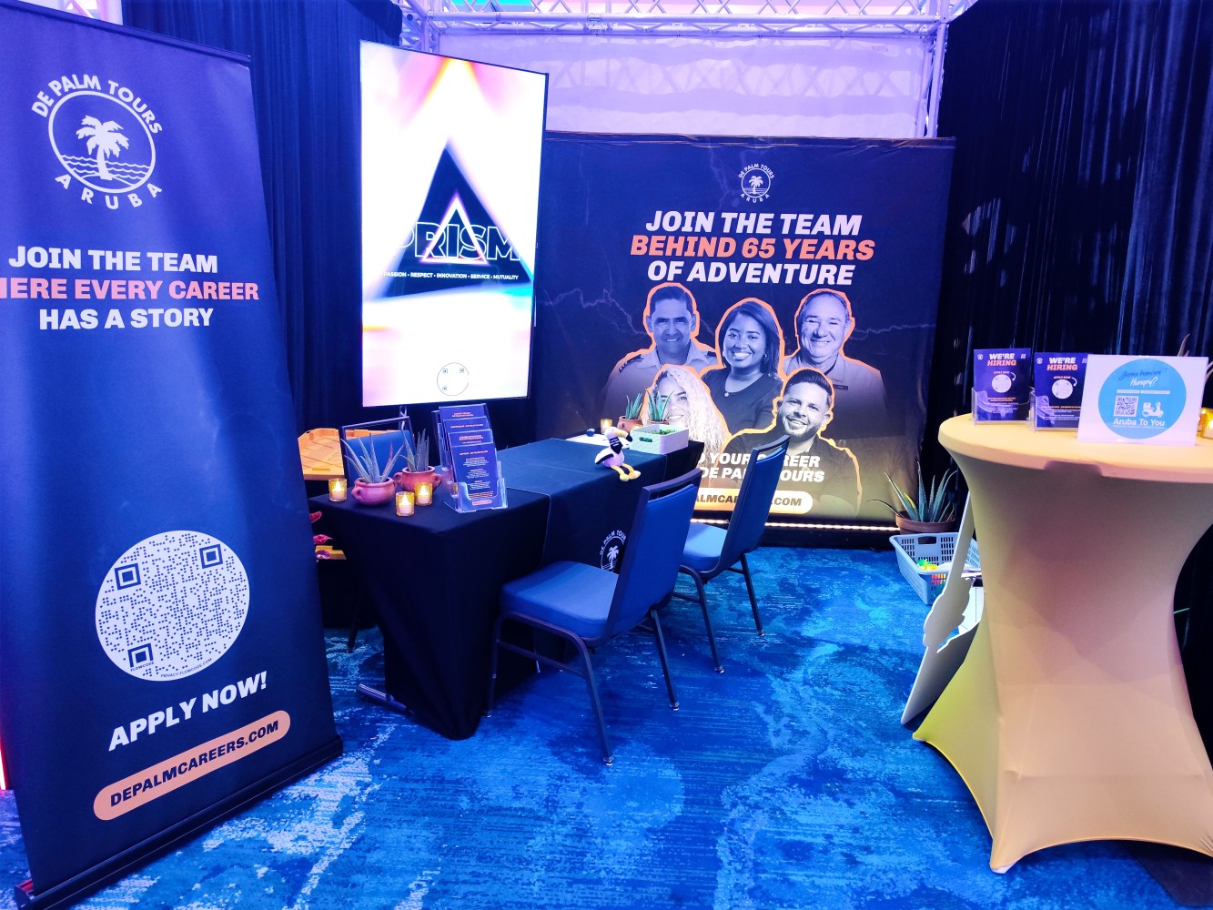 Trade show booth with posters and tables for De Palm Tours Aruba recruitment.