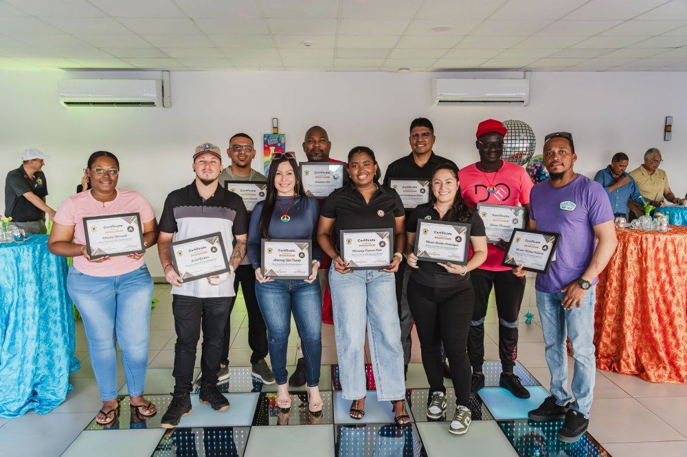Group of people holding certificates, standing in a room with colorful decorations.
