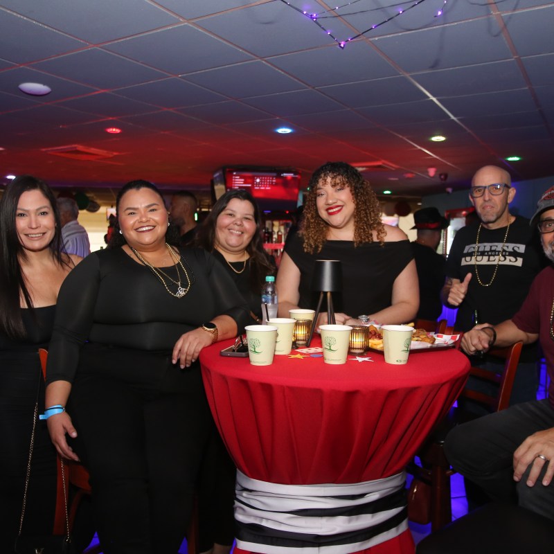 Group of people smiling around a table with drinks at a party venue.