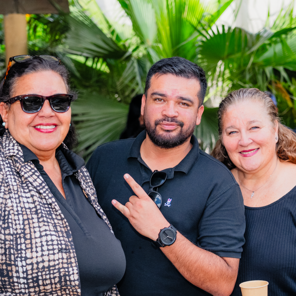 Three people smiling at the camera in a garden setting.