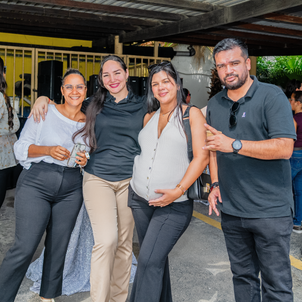 Four people posing and smiling at an outdoor gathering under a metal roof.