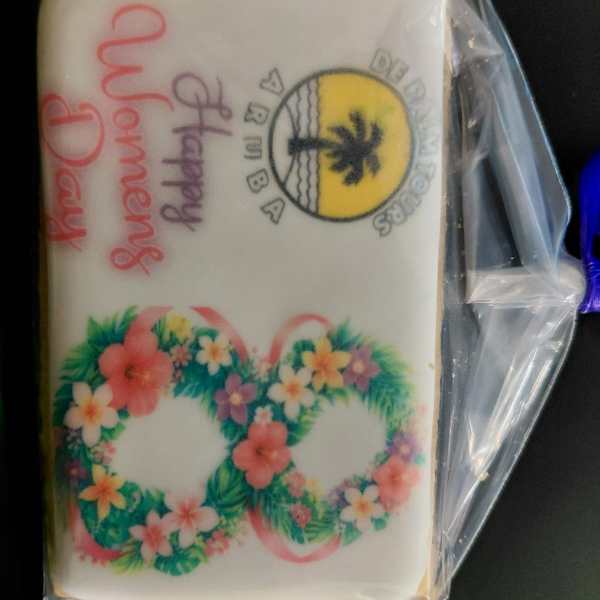 A decorated cookie with 'Happy Women's Day' and floral design in a plastic wrap.