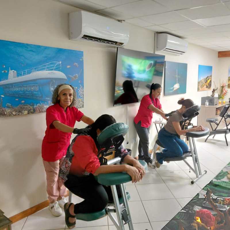 Two people receiving chair massages in a room with ocean-themed art.