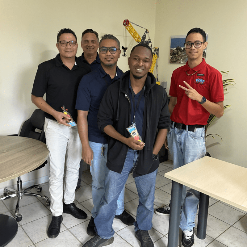 Five men standing together indoors, some holding snacks.