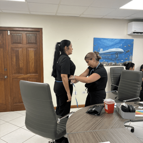 Person measuring another's waist with tape in an office with a submarine painting.