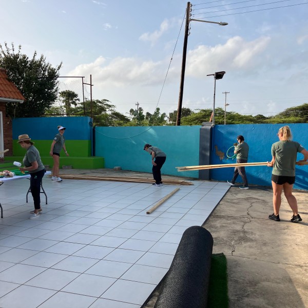 People working on a tiled outdoor area with building materials.