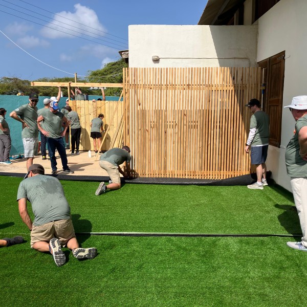 People installing artificial turf in a courtyard on a sunny day.