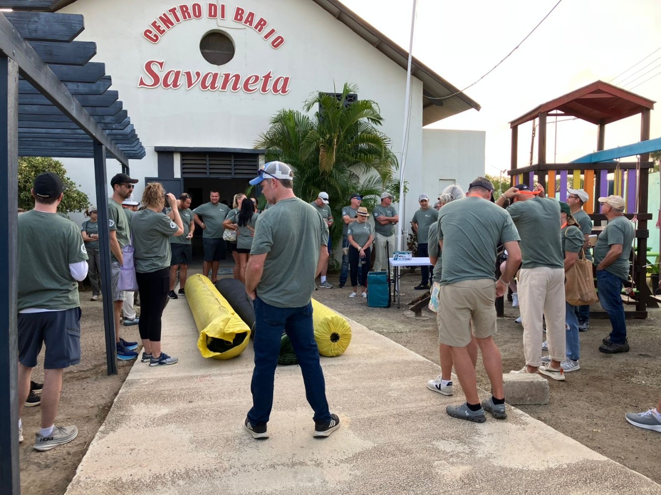 Group of people in green shirts gathering outside a community center.