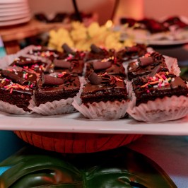 Platter of chocolate brownies with sprinkles and chocolate curls in paper cups.