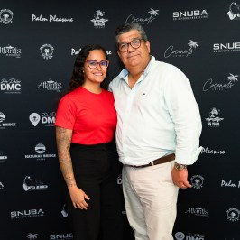 Two people smiling in front of a backdrop with logos.