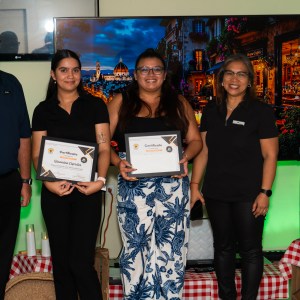 Four people posing with certificates at an indoor event with a colorful backdrop.