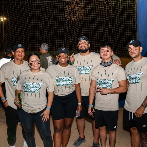 Group of six people in matching 'Mosh Pit Madness' shirts at an outdoor event.