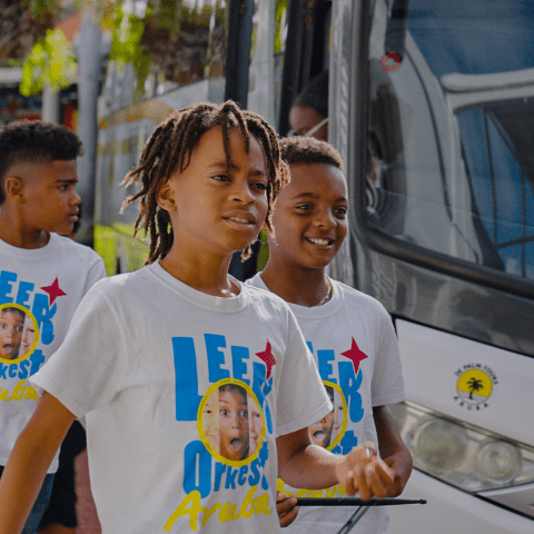 Three boys wearing matching themed T-shirts walking beside a bus.