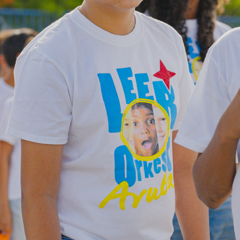 Children wearing T-shirts with bright graphics and text, standing in a group outdoors.