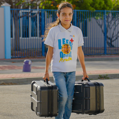 Smiling girl with long hair carrying two black cases outdoors.