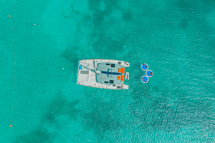 Aerial view of a catamaran and floats on clear turquoise water.