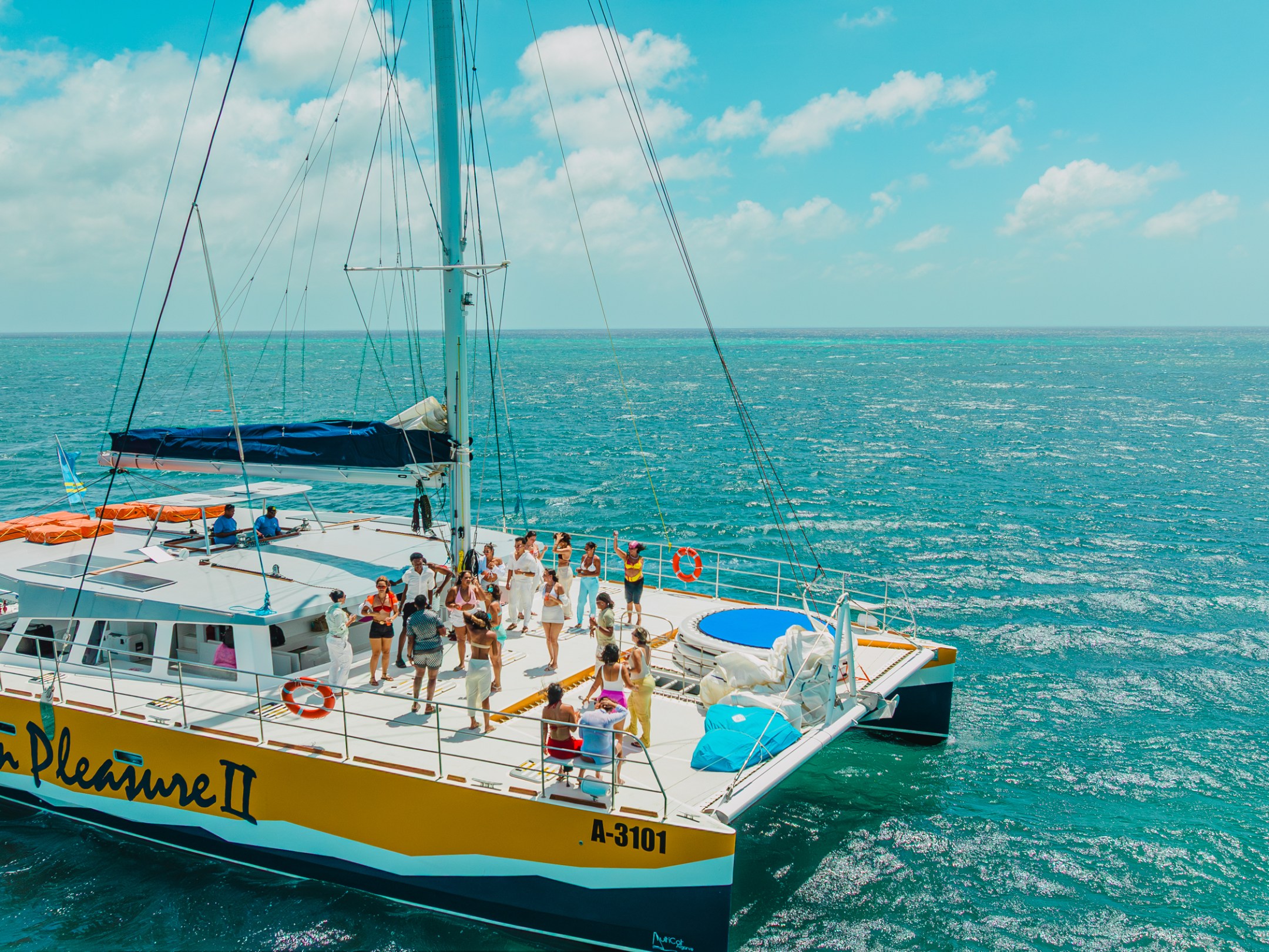 People on a large catamaran boat in calm blue sea under clear skies.