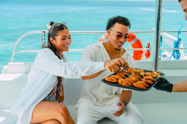 Two people on a boat enjoying snacks from a tray.