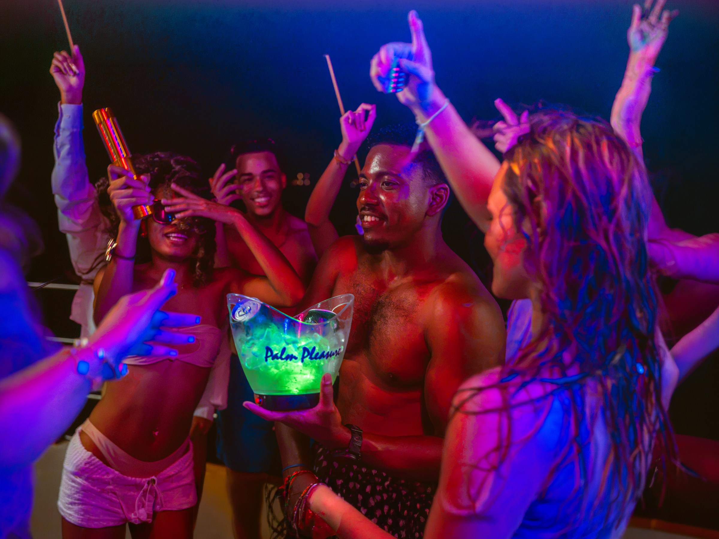 Group of people dancing at a party under colorful lights.