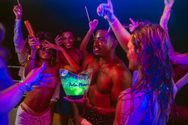 Group of people dancing at a party under colorful lights.