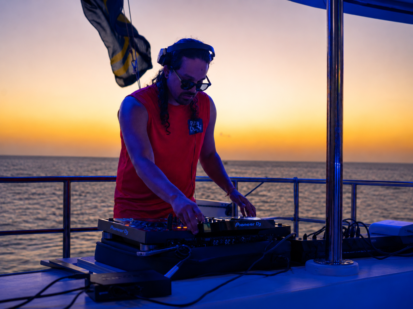 DJ playing music on a boat at sunset.