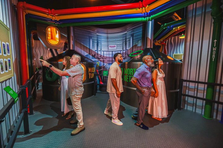 Group of people in a colorful interactive exhibit with pipes and tanks.