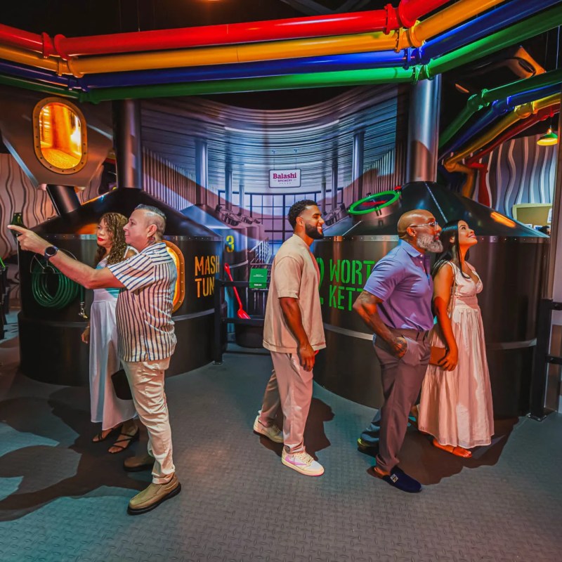 Group of people in a colorful interactive exhibit with pipes and tanks.