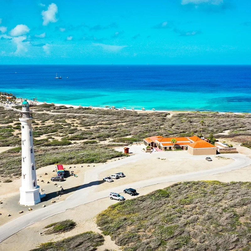 Aerial view of a coastal lighthouse near the ocean with clear skies.
